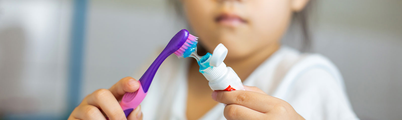 A child s hand holding a toothbrush with toothpaste on it.