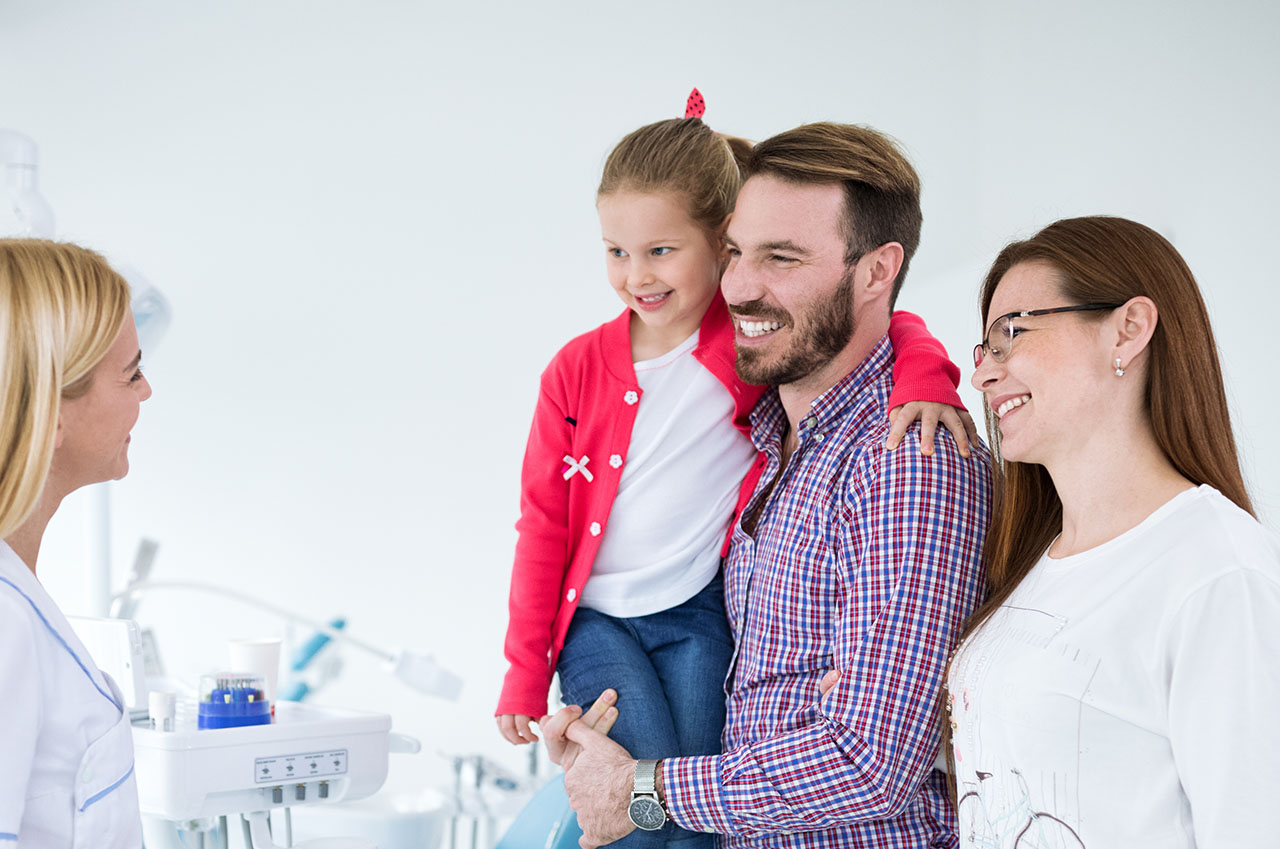 A family poses with a dental professional in a dental office setting.