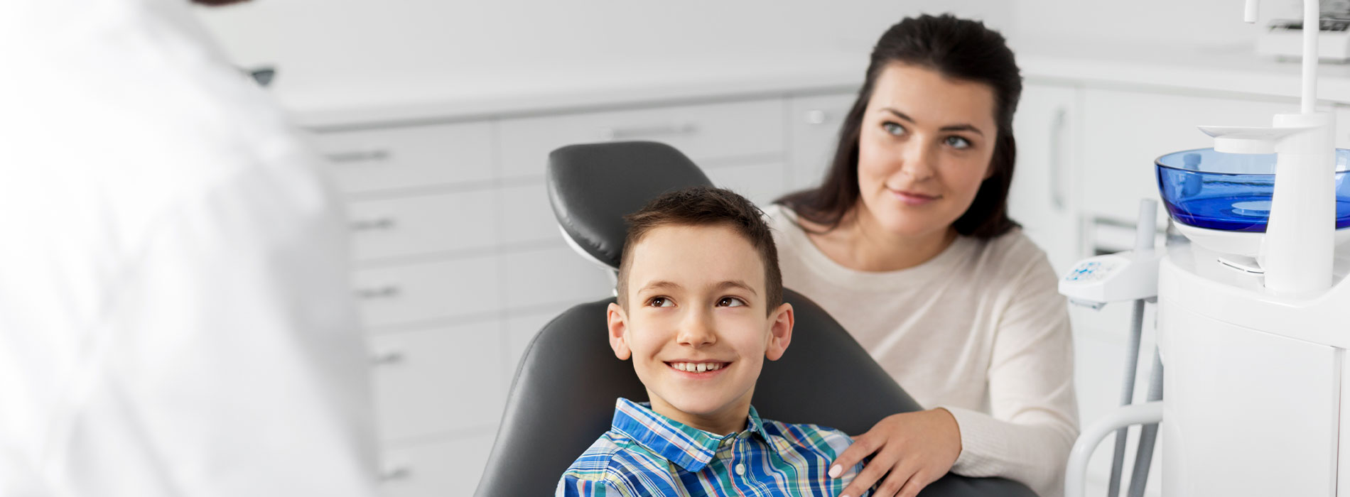 A photograph of a dental office with a dentist and patient.