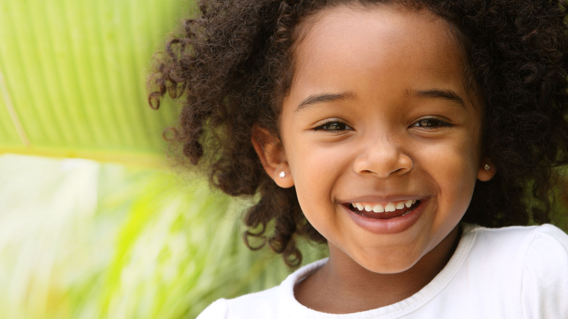 A young child with curly hair smiling at the camera.